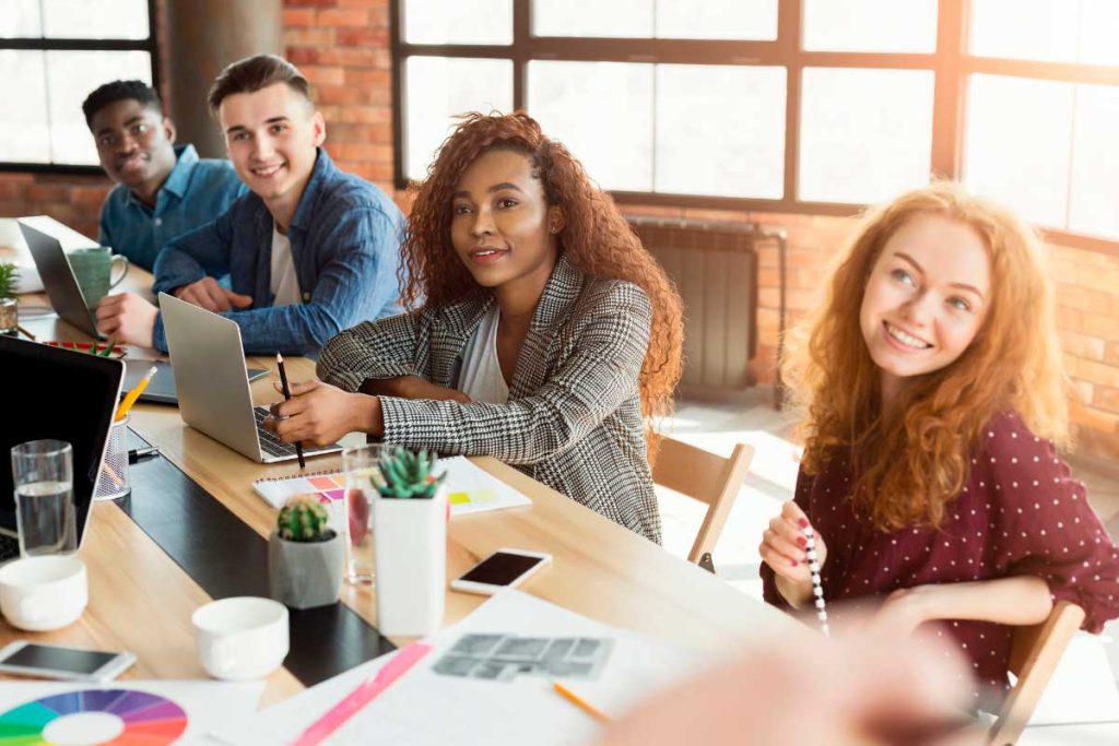 Mesa en espacio de trabajo con gente y sus portátiles