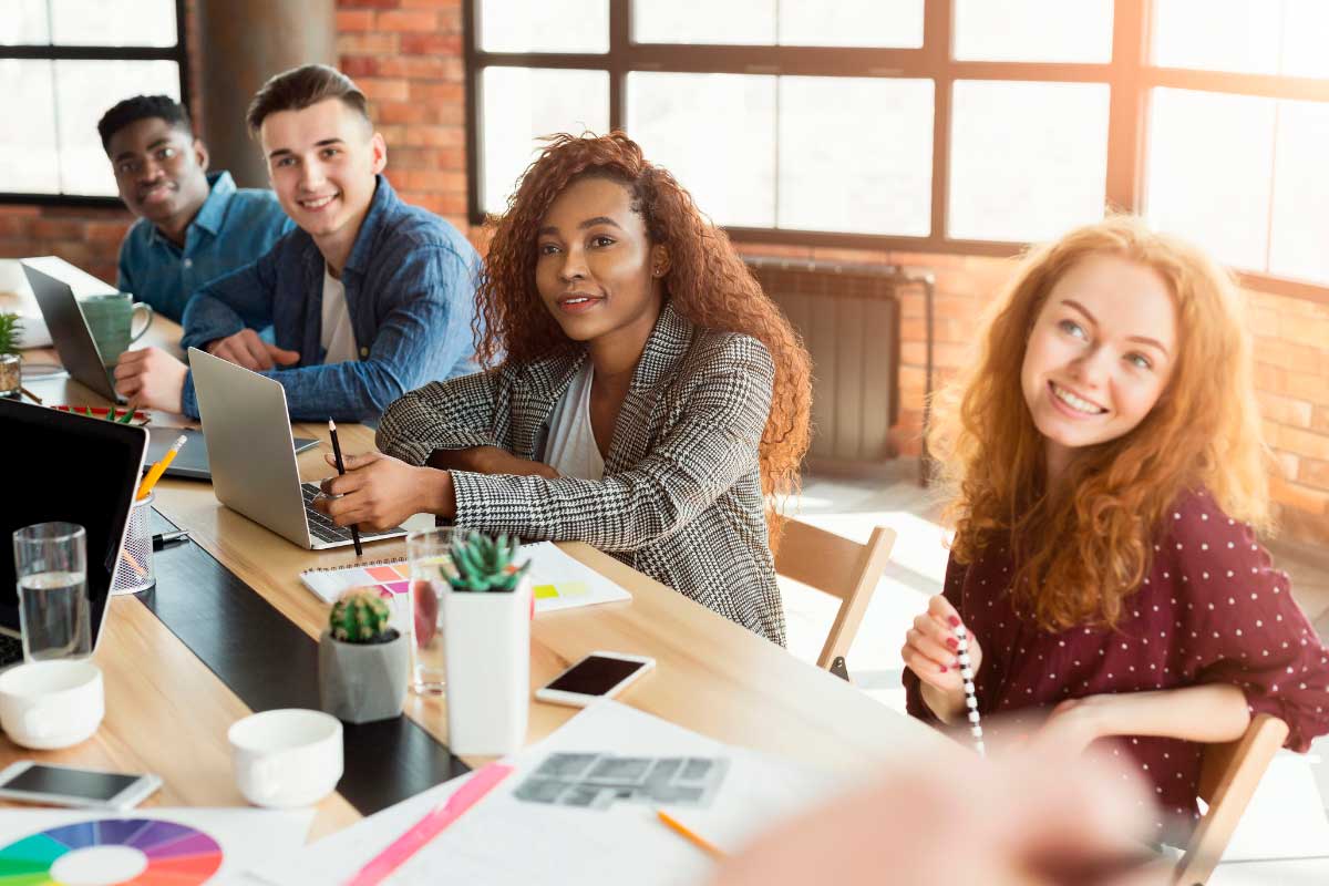 Mesa en espacio de trabajo con gente y sus portátiles