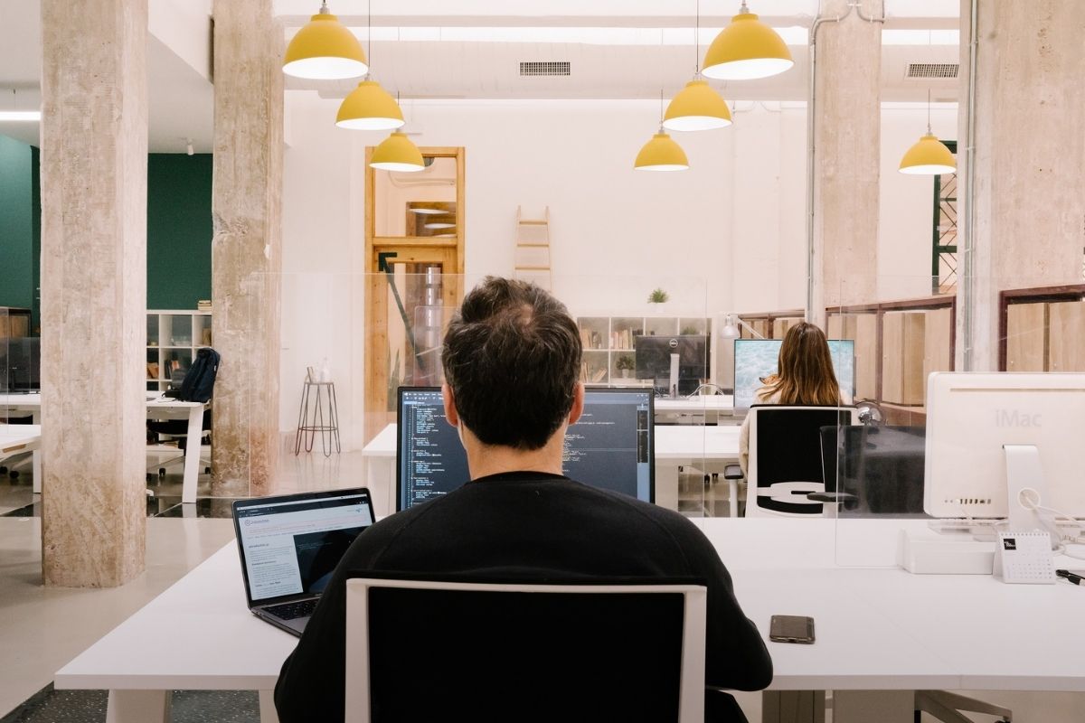Imagen de coworking luminoso con mesas de trabajo espaciosas y gente trabajando con su ordenador
