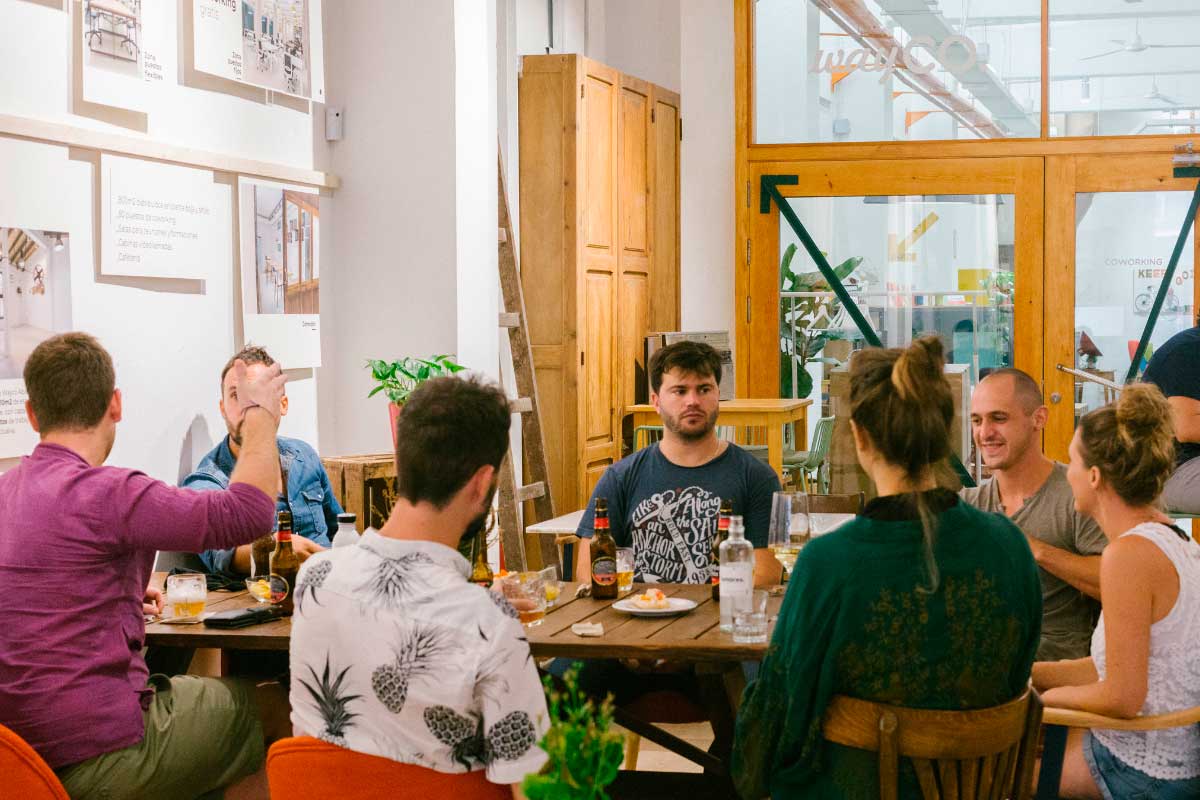 Imagen de una cafetería con varias personas charlando alrededor de una mesa