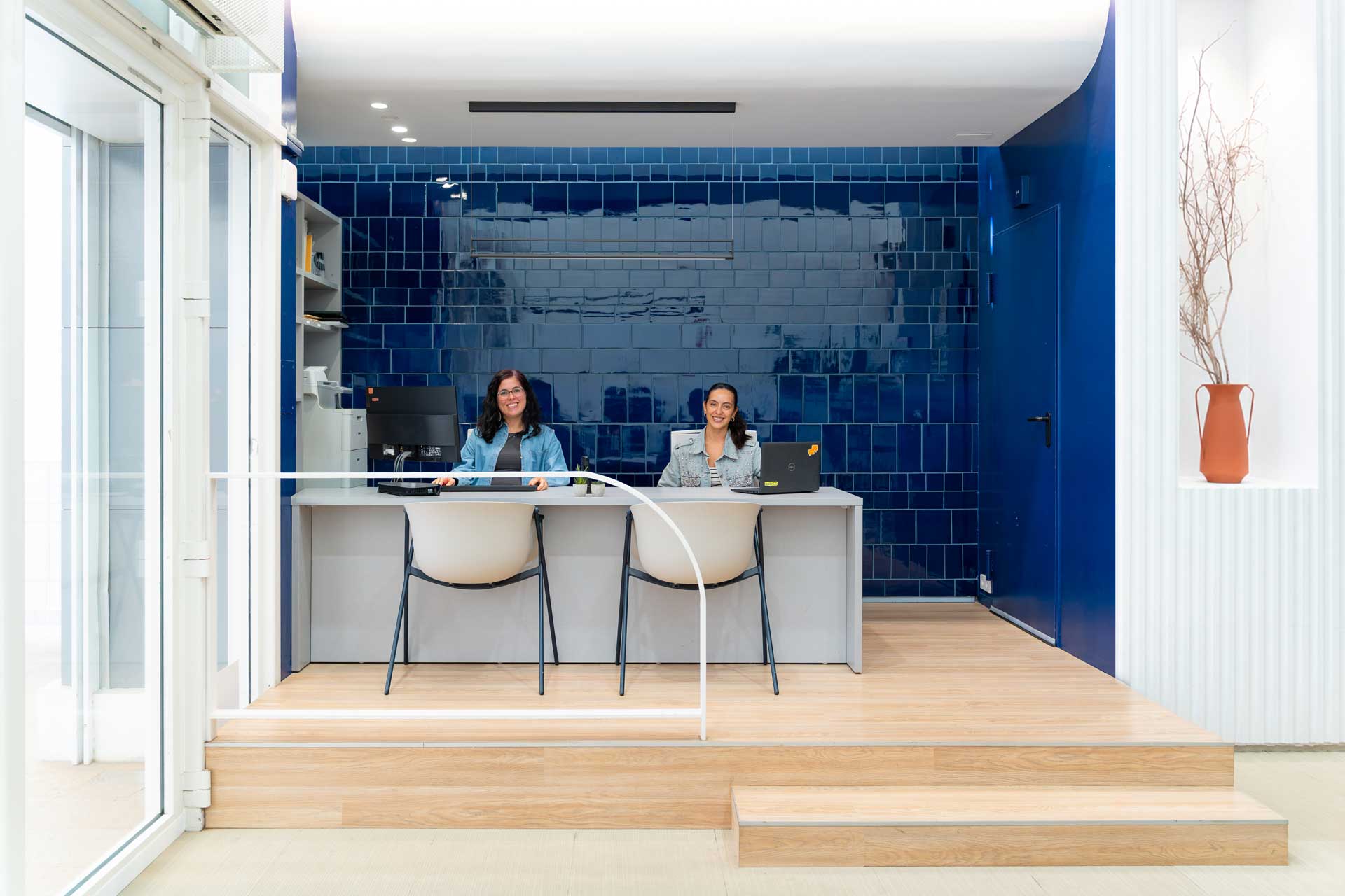 Dos mujeres sonrientes en el mostrador de una recepción