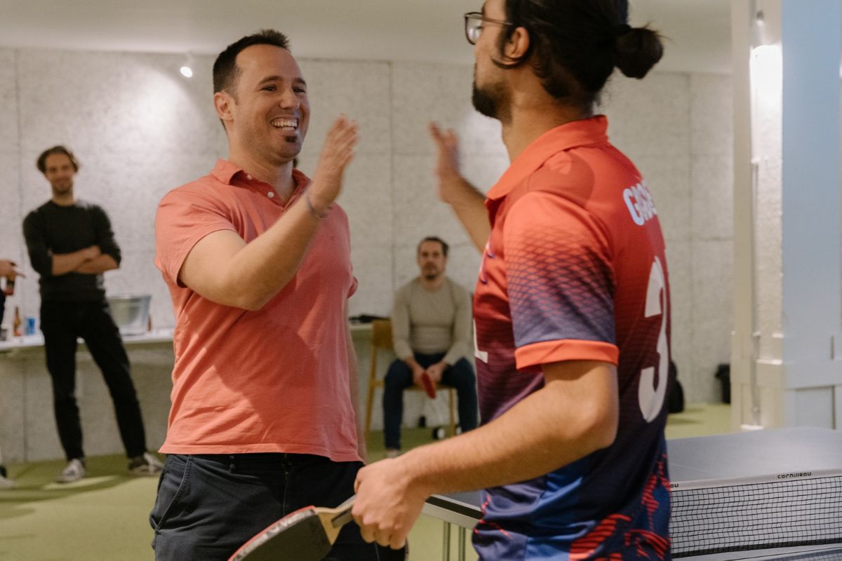 Imagen de dos chicos a punto de chocar las manos para celebrar una partida ping pong